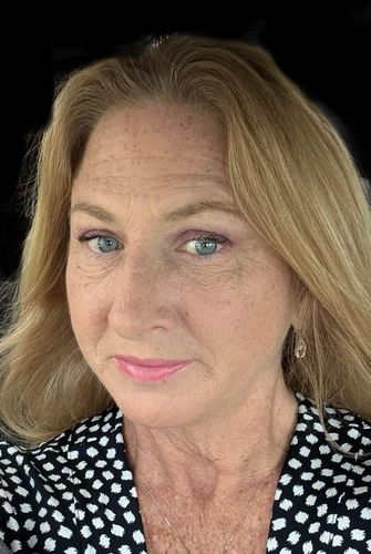 Close-up portrait of a woman with blonde hair and blue eyes.