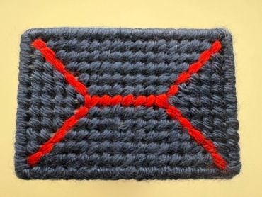 A rectangular crochet piece with red lines.