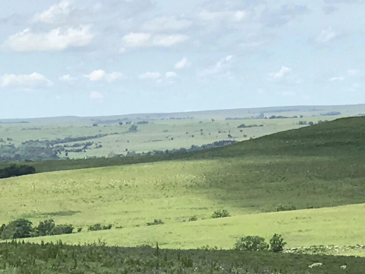 Vast green rolling hills under a partly cloudy sky.