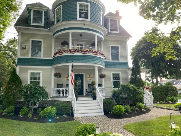 A charming two-story house with a porch and patriotic decorations.