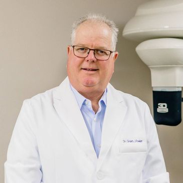 A smiling doctor in a white lab coat standing in a medical office.