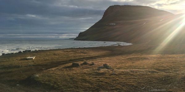 late spring sunset in arctic bay, Nunavut. melting sea ice, qamutiik, and hillside glowing in the af
