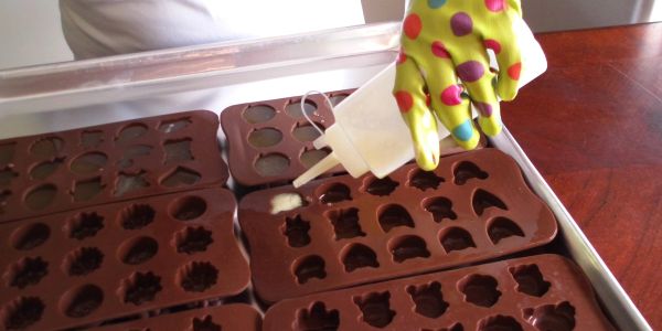 Filling molds with a creamy substance using a squeeze bottle.