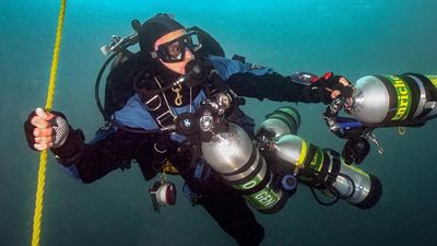 A Diver Diving With Cylinders To Side