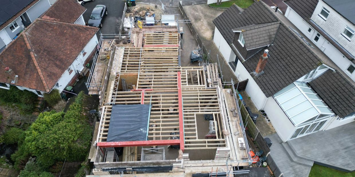 Aerial view of a wooden framework under construction on a residential site.