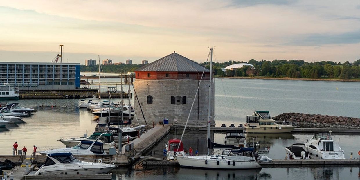Historic stone fort surrounded by boats in a calm marina at sunset.