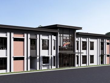 Modern two-story building with large windows and brick accents in a landscaped setting.