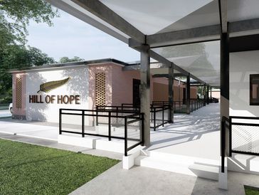 Modern building entrance with "Hill of Hope" sign and accessible ramps under a shaded walkway.