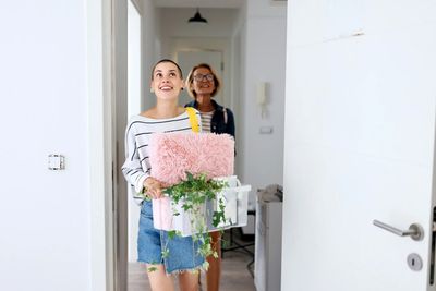 happy student arriving in her university room with her belongings, followed by her mum