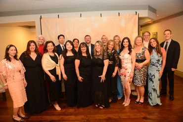 Group of people dressed formally posing indoors with a backdrop.