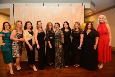 Group of women dressed elegantly posing at an event.