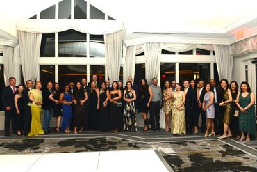 A large group of people dressed elegantly posing indoors in a well-lit room.