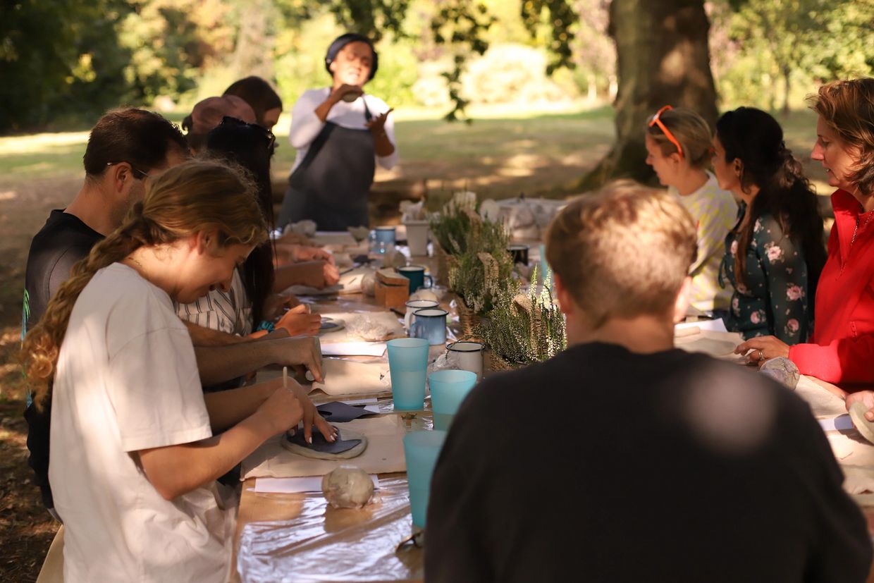 People engaging in an outdoor pottery class on a sunny day.