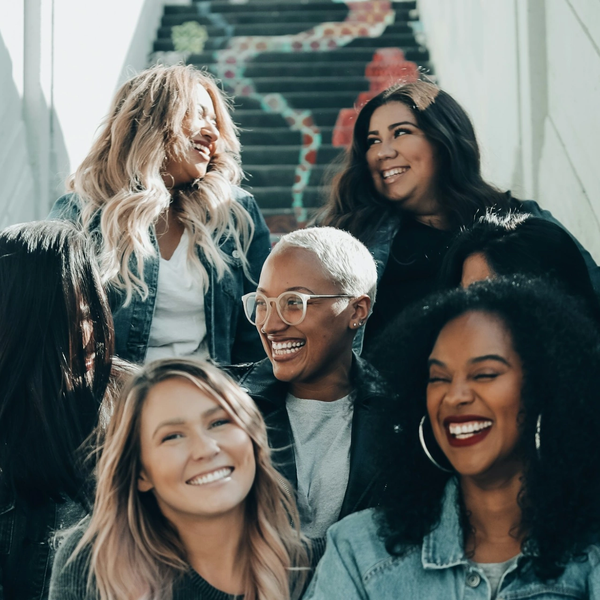 Group of diverse women laughing together on stairs.
