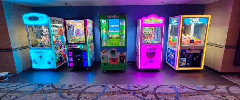 Colorful claw machines lined up in a gaming arcade corridor.