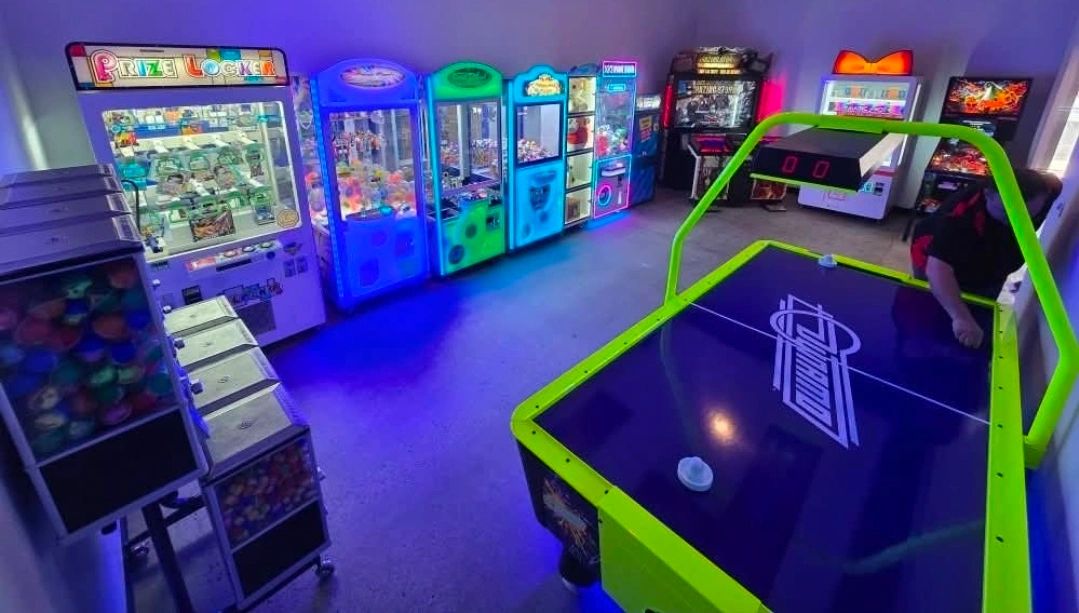 A vibrant arcade room with claw machines and an air hockey table.