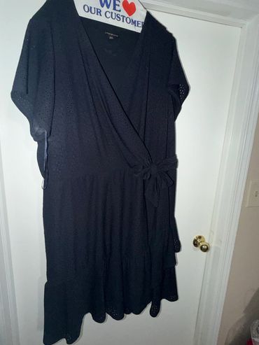 Black wrap dress hanging on a door with a customer appreciation sign above.