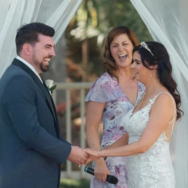 A joyful couple holding hands during their wedding ceremony.