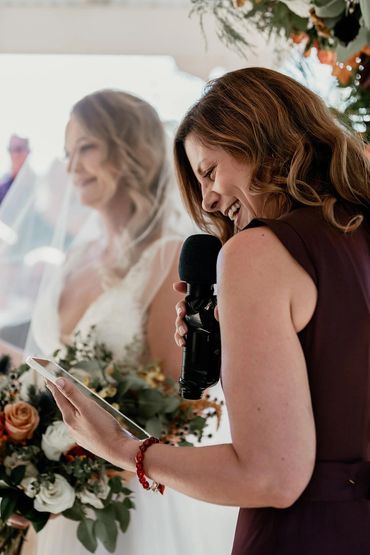 Woman joyfully speaking into a microphone at a wedding ceremony.