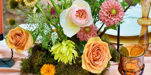 Elegant floral centerpiece with roses and daisies on a decorated table.