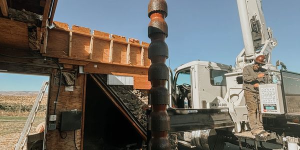 Worker operating crane truck at construction site under blue sky.