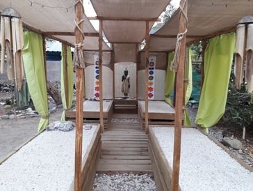 An outdoor scene showing a row of small, white rental cabins lining a gravel driveway. 