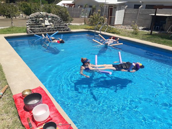An outdoor photo on a sunny day showing three people floating and relaxing in a bright. 