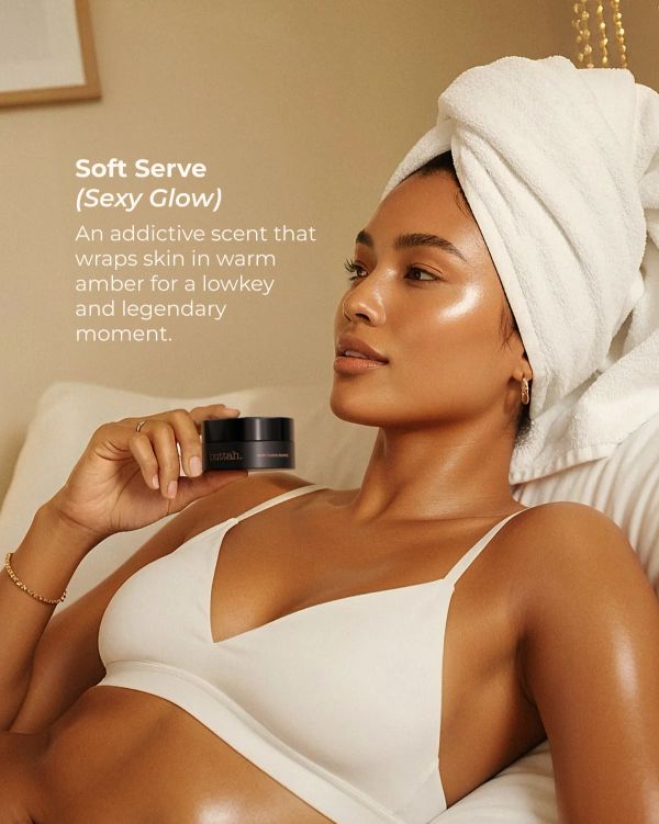 Woman with glowing skin holds a skincare product, wrapped in a towel.