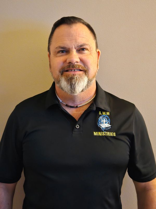 Man wearing a black S.W.M Ministries polo shirt smiling.