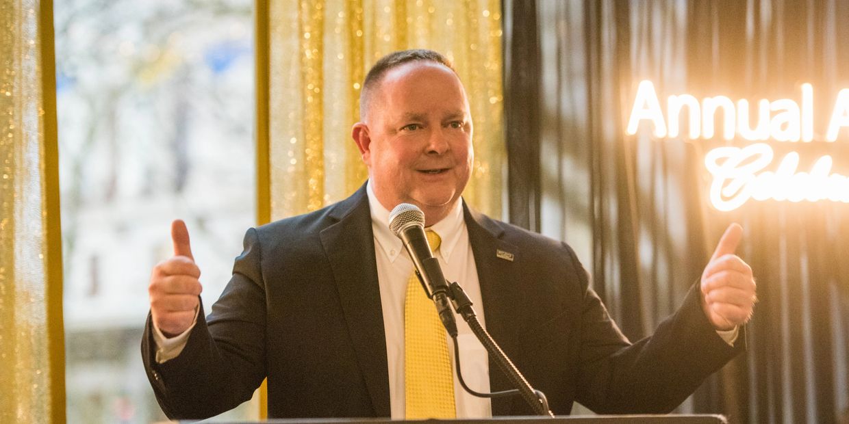 Dan Powell speaking at an awards ceremony after winning "Manager of the Year" award.