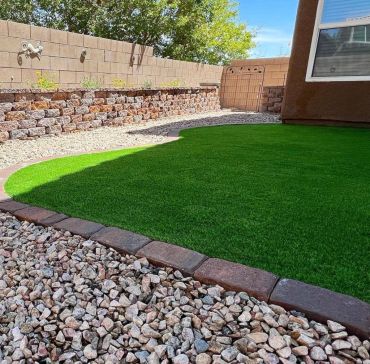 Well-maintained backyard with artificial grass and decorative stones.