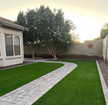Curved stone pathway through a well-maintained green lawn beside a house.