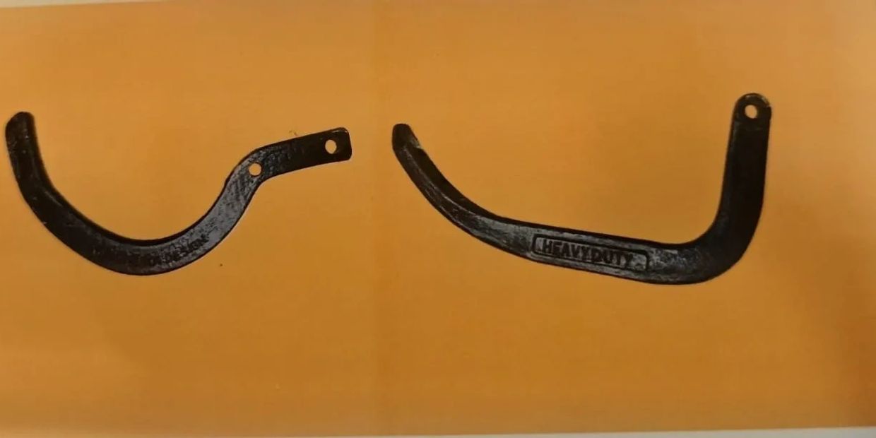 Two black metal hooks with mounting holes against an orange background.