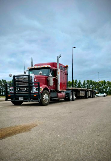 Un camion remorque rouge garé sur une route dégagée.