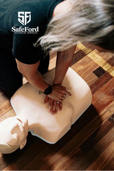 Person performing CPR on a training mannequin indoors.