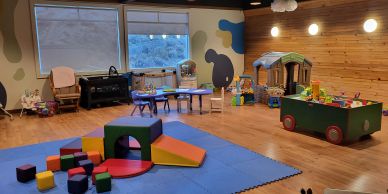 Colorful indoor children's playroom with toys and soft mats.