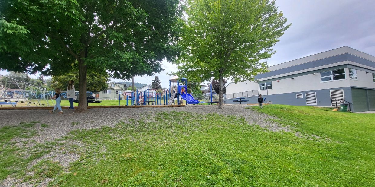 Children playing in a school playground with slides and swings.