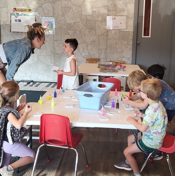 Teacher engaging with a child in a colorful classroom.