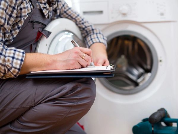 Repairman is repairing a washing machine. Entering malfunction