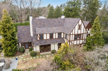 A two-story Tudor-style house surrounded by trees.