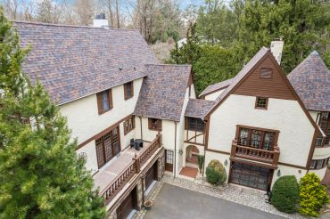 Large, Tudor-style house with steep roofs and brown window frames.