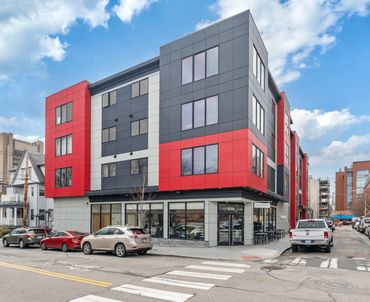 New exterior construction of multi dwelling building with residential units and a commercial space.