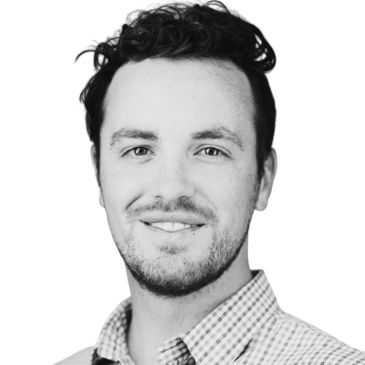Black and white headshot of a smiling man with curly hair.