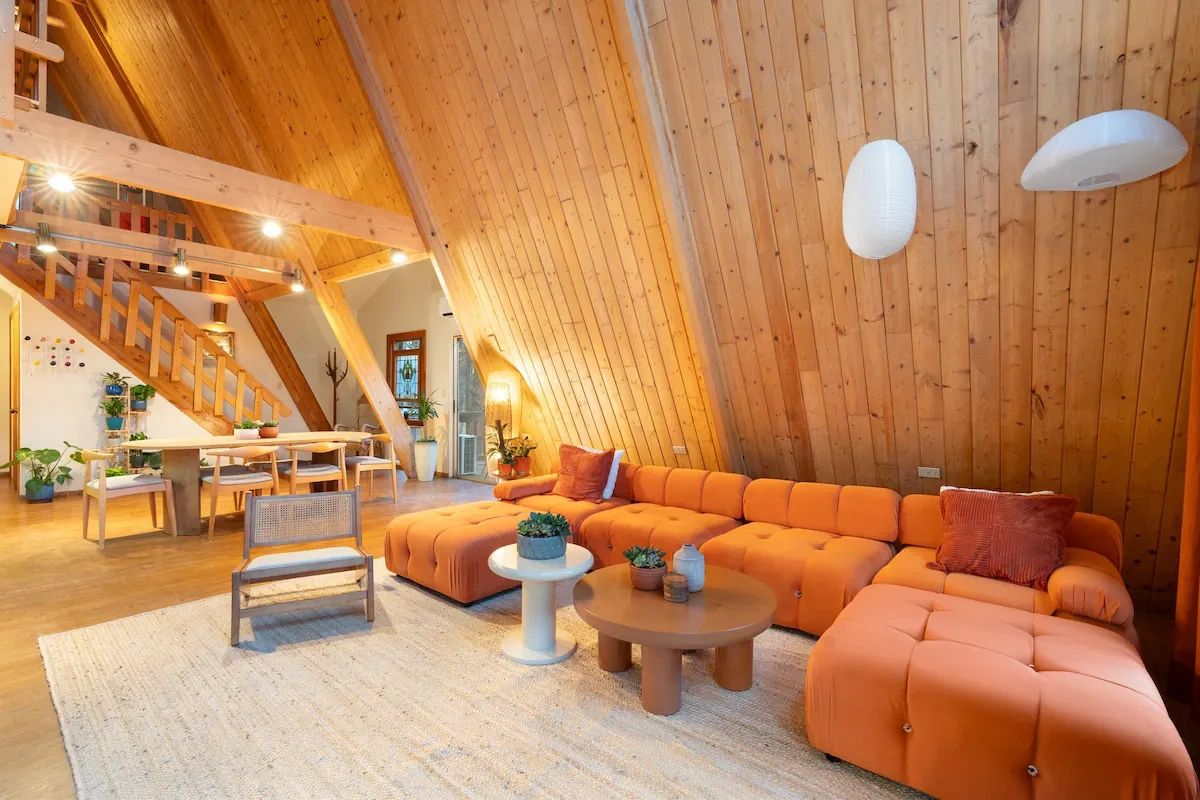 Cozy wooden attic living room with orange sofa.