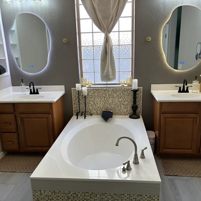 Modern bathroom with a central bathtub and two illuminated mirrors.
