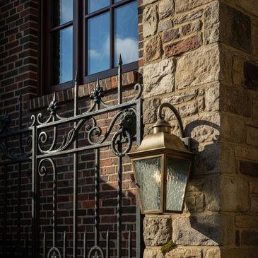 Decorative iron gate and vintage lantern on a stone and brick building.