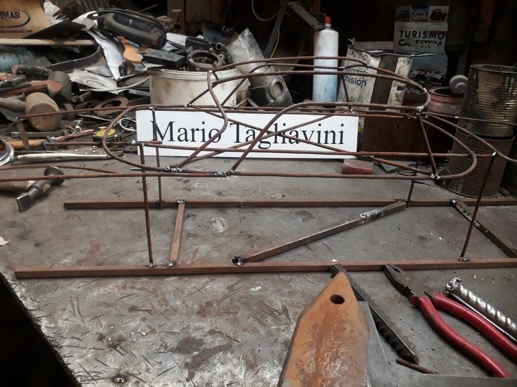 Wireframe model of a car on a workbench with tools and parts.