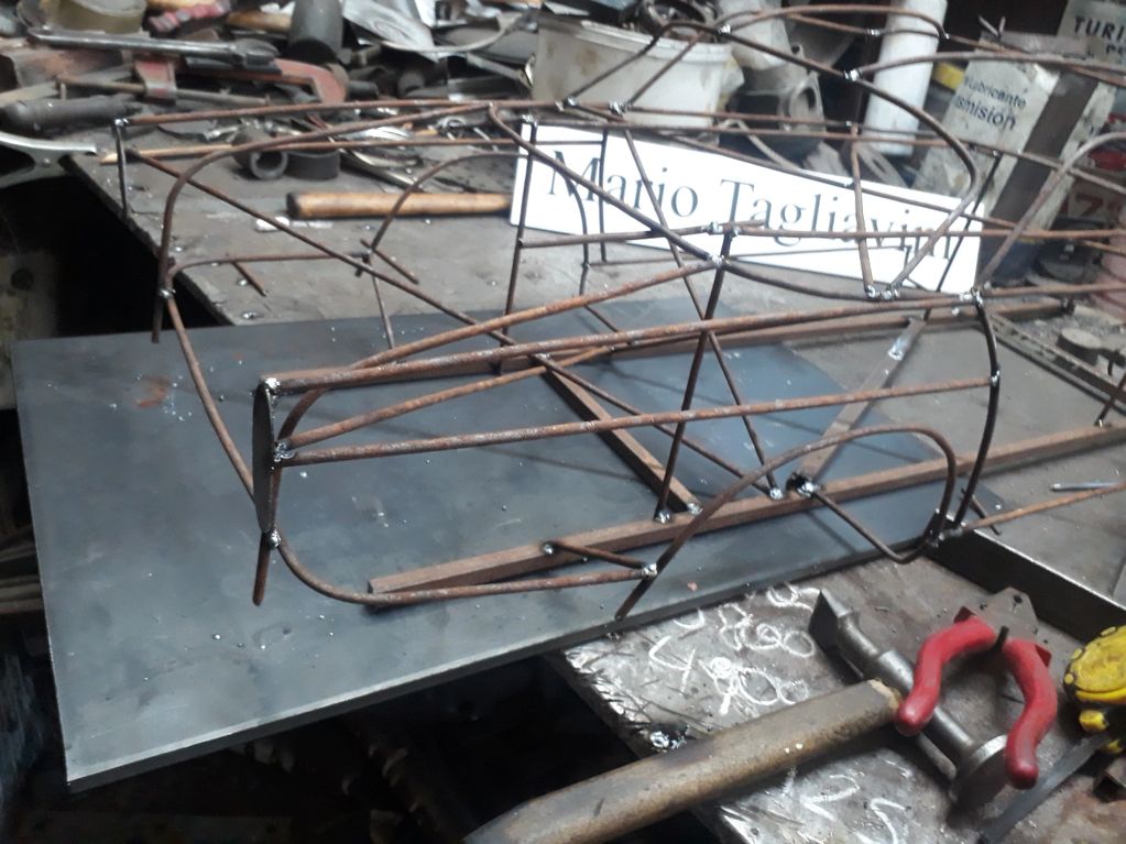 Metal frame structure on a workshop table with tools around.