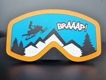 Patch showing a snowmobile jumping over mountains with the word 'BRAAAP!'.