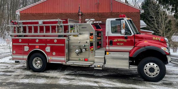 Red fire truck parked outside a brick building.